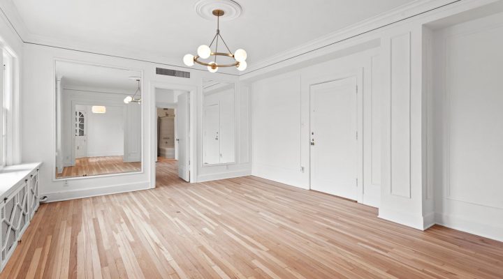 Bright and spacious living room with elegant light wood flooring, furnished minimally to accentuate the expansive area.
